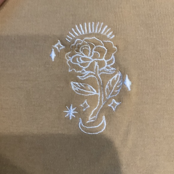 Tan colored shirt that has a flower on it - Picture 2 of 3